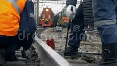 铁路工人在工作。 铁路线上穿橙色制服的铁路工人。